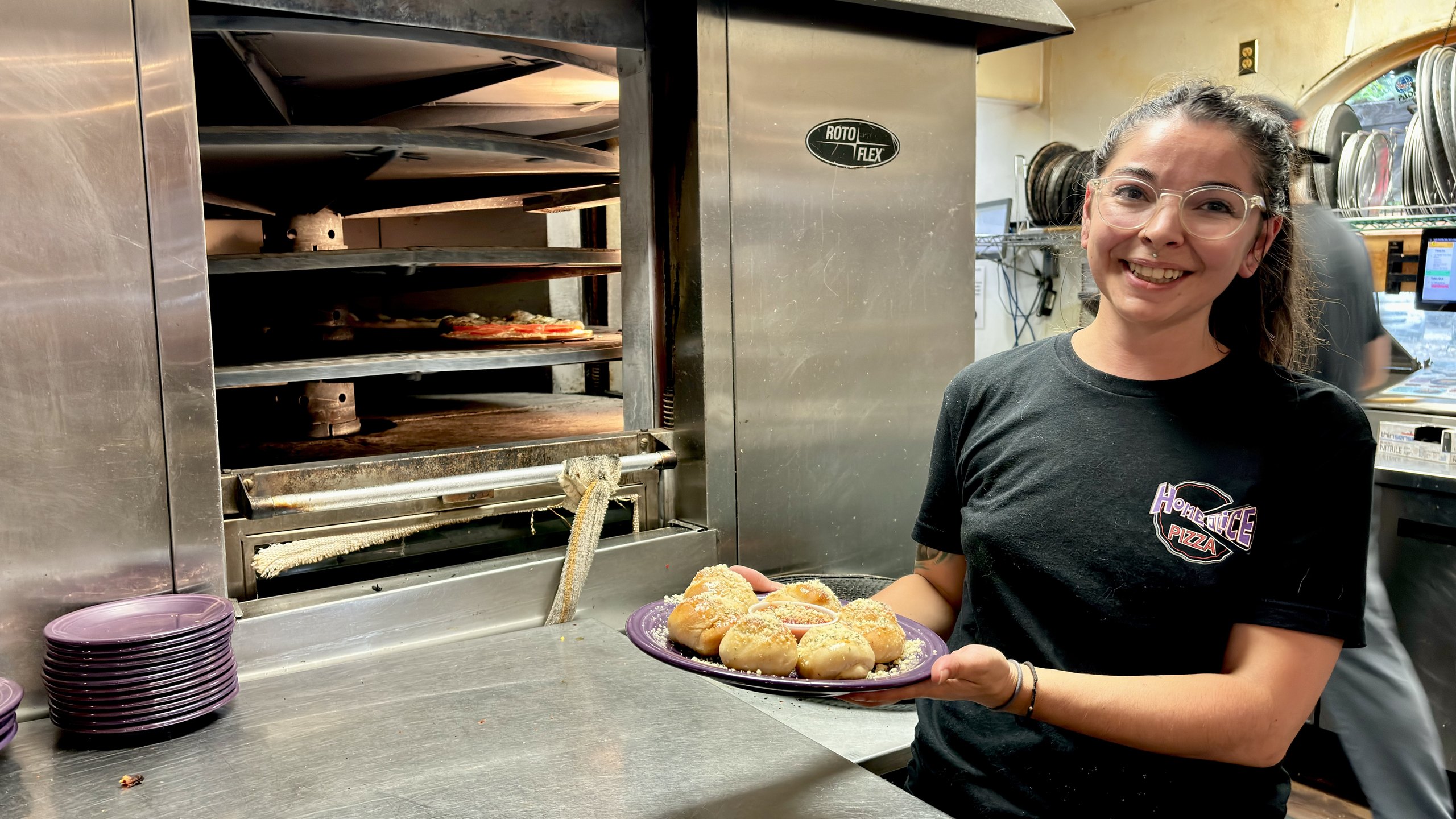 A HomeSlice staffer serving a fresh plate at College Drive