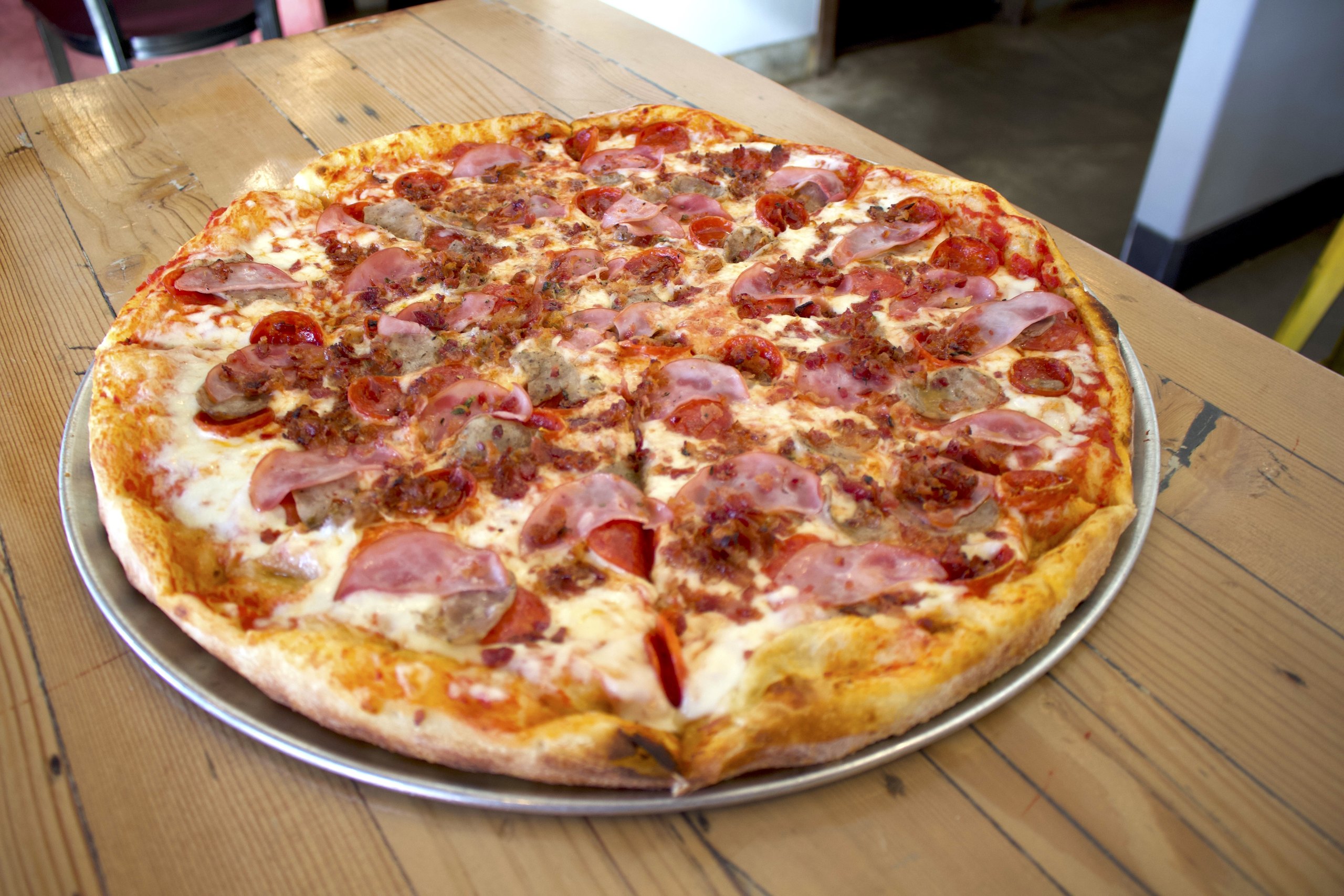 A loaded HomeSlice pizza fresh on the table