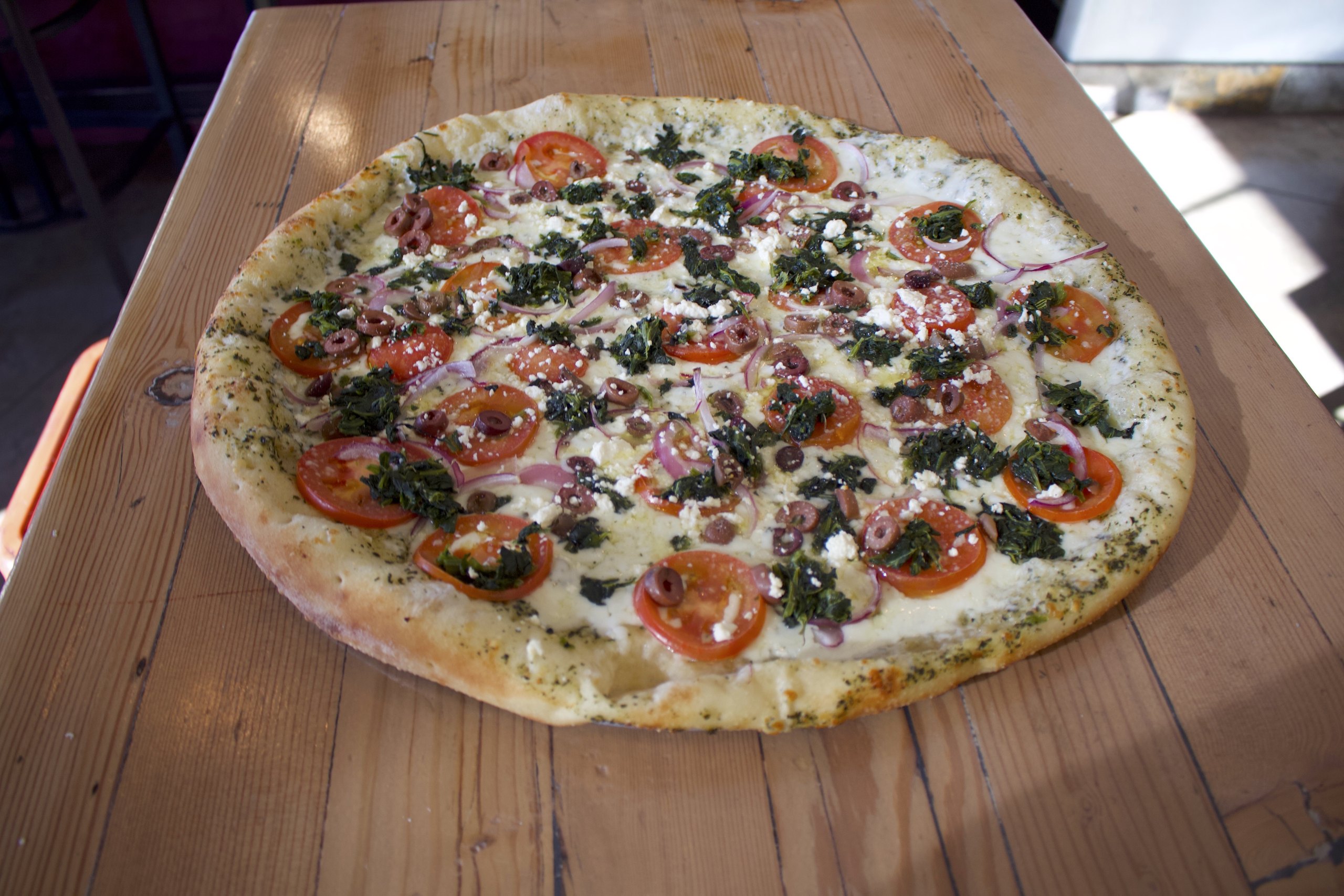 Close-up of a HomeSlice white pizza with fresh toppings