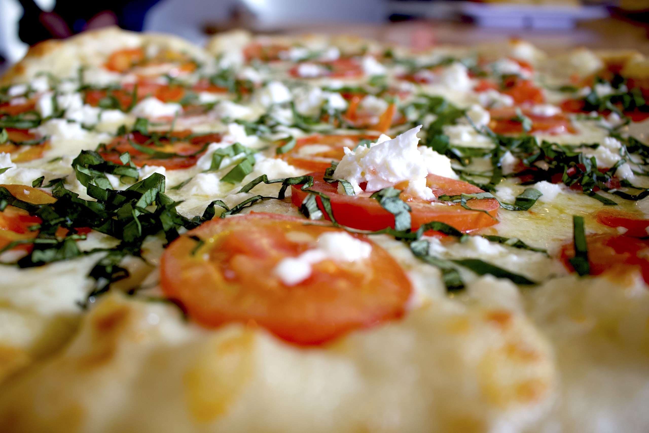 Close-up of a HomeSlice white pizza with fresh toppings