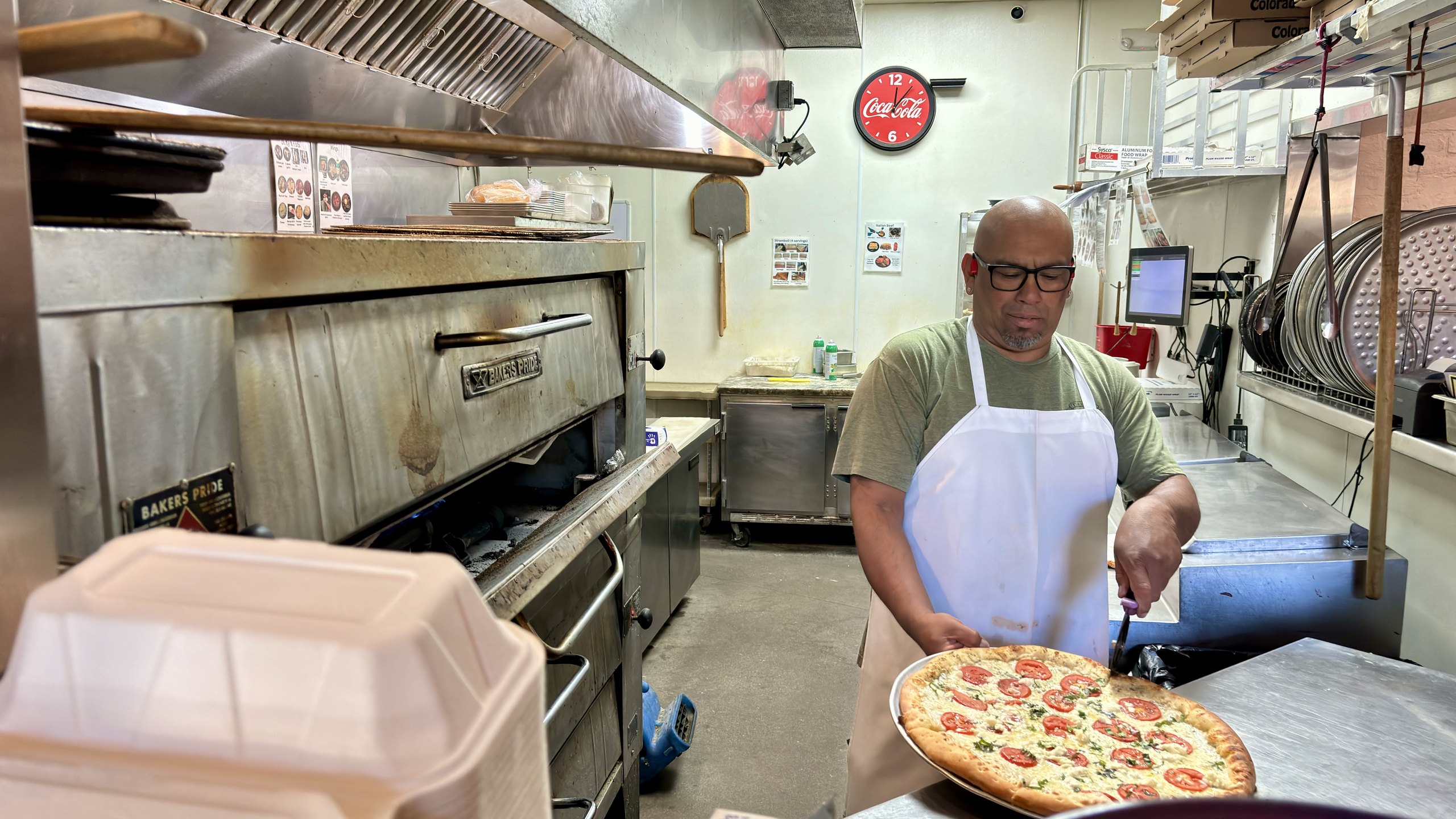 A cook sliding a fresh HomeSlice pizza into the oven at Three Springs