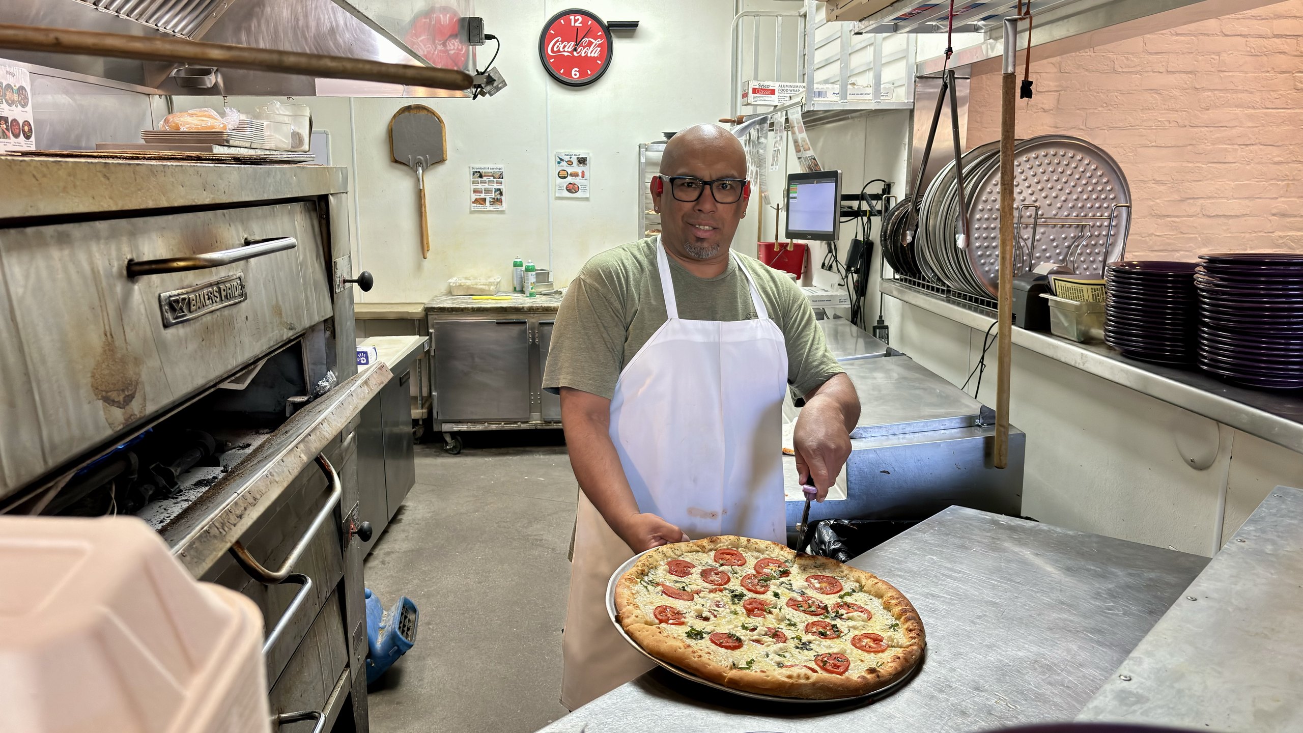 A HomeSlice cook sliding a fresh pizza into the oven