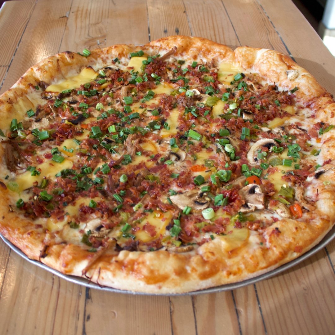 Overhead shot of a pizza topped with bacon and green onion