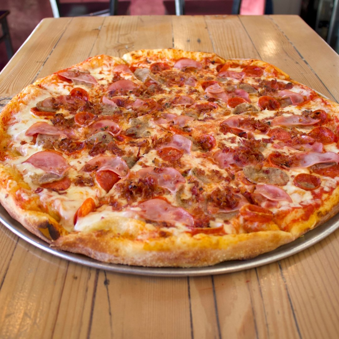 Overhead shot of the Meatzza specialty pizza with pepperoni, Italian sausage, bacon and ham